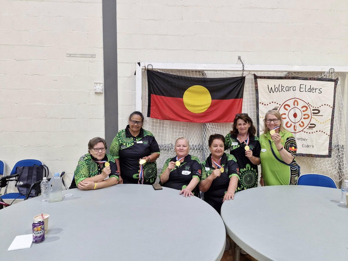 A group of Wolkara Elders proudly displaying medals in front of the Aboriginal flag and Wolkara Elders banner.
